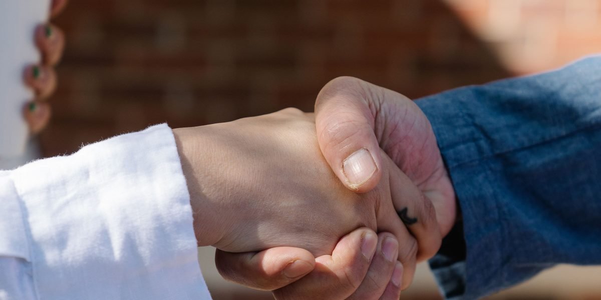 Two professionals shaking hands, symbolizing a successful hiring outcome or partnership after a meeting.