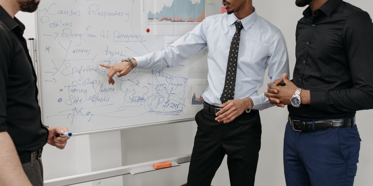 A team of professionals actively collaborating on a whiteboard, demonstrating teamwork and problem-solving in action.