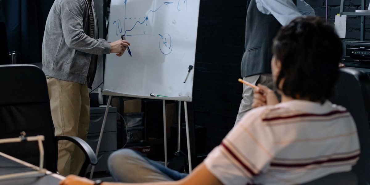 A diverse team collaborating actively, brainstorming and outlining solutions on a whiteboard during a meeting.